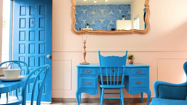 Une pièce avec une porte bleue, un bureau bleu assorti et une chaise bleue assortie.