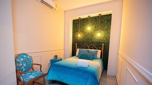 Une chambre à coucher comprenant un lit, une chaise, une table de chevet et un luminaire fixé au mur.