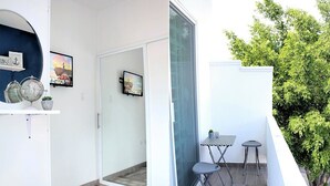 Un appartement moderne doté d’un balcon, d’une porte-fenêtre coulissante et d’un petit espace extérieur aménagé pour s’asseoir.