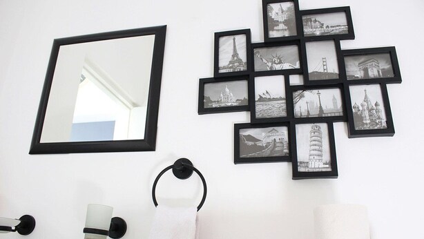 Une salle de bain équipée d’un miroir, d’un lavabo, d’un porte-serviettes et d’un collage de photos de monuments célèbres accroché au mur.