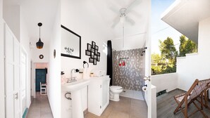 Un baño moderno con ducha, inodoro y lavamanos. Hay un ventilador de techo y una pequeña mesa con una silla.