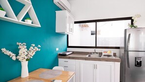 Una cocina moderna con armarios blancos, un refrigerador de acero inoxidable, un ventanal con vistas y una pared de acento color aguamarina.
