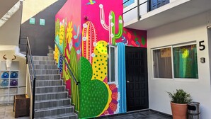 Eine farbenfrohe Gebäudefassade mit einer Treppe, einer schwarzen Tür und einem Blumentopf.