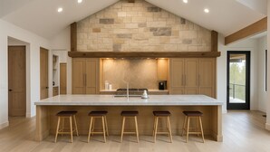 Una cocina amplia con una isla grande, taburetes de madera y una pared decorativa de piedra.