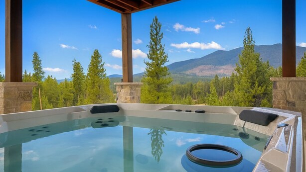 Un jacuzzi con vistas despejadas a montañas y árboles.