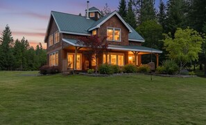 A two-story house with a green roof, large windows, and a covered porch.
