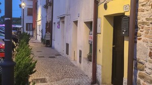 Une rue pavée bordée de bâtiments des deux côtés, un lampadaire et une enseigne indiquant un commerce.