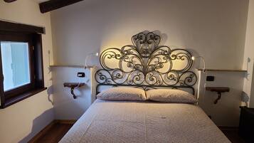 Un dormitorio con una cama, dos mesitas de noche, una ventana y un cabecero decorativo de metal.