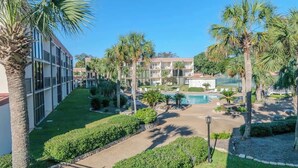 Une cour d’hôtel avec une piscine, des palmiers et un bâtiment doté de nombreux balcons.