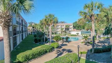 A hotel courtyard with a swimming pool, palm trees, and a building with multiple balconies.