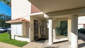 Une entrée d’immeuble avec une boîte aux lettres, un ascenseur et un espace abrité doté de colonnes.