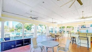 A spacious indoor area with multiple seating arrangements, ceiling fans, and large windows providing natural light. - Legacy Villa 203 - 2 Bedroom 2 Bath With Garage in a Beachside Neighborhood (Gulfport)
