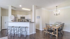 A modern kitchen with white cabinets, a central island, and bar stools. - Legacy Villa 203 - 2 Bedroom 2 Bath With Garage in a Beachside Neighborhood (Gulfport)