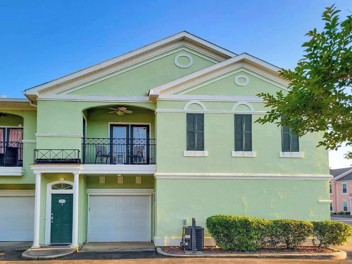 Una casa de dos pisos con fachada verde, un balcón y un garaje.