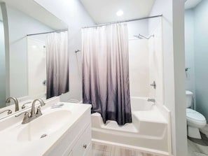 A bathroom with a double sink, a bathtub, and a toilet.