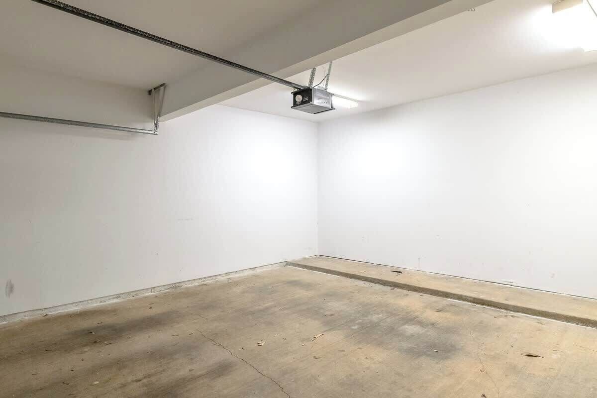 Una habitación con paredes blancas, piso de concreto y un proyector en el techo.