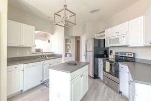 A modern kitchen with white cabinets, stainless steel appliances, and a central island.
