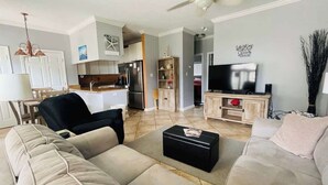 Un salon avec un canapé, une table basse, un téléviseur et un ventilateur de plafond.