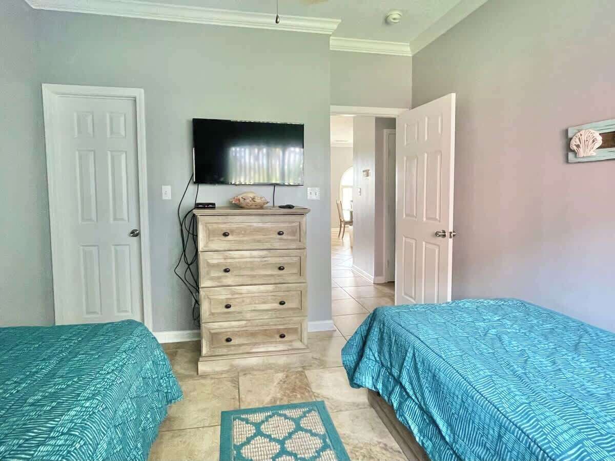 Een slaapkamer met twee bedden, een dressoir en een televisie.