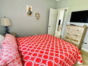 A bedroom with a bed, a dresser, a television, and a door. - 146 Beau Clair - Beachside Townhome With Pool in Long Beach (Long Beach)