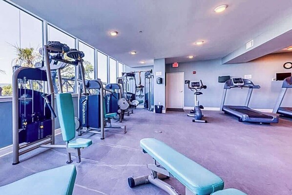 A gym with various exercise equipment, including treadmills and weight machines, and a bench.