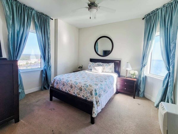 Une chambre à coucher avec un lit, une table de chevet, une commode, un miroir et des rideaux.