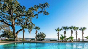 A swimming pool with lounge chairs and palm trees. - The Cobalt View (Gulfport)