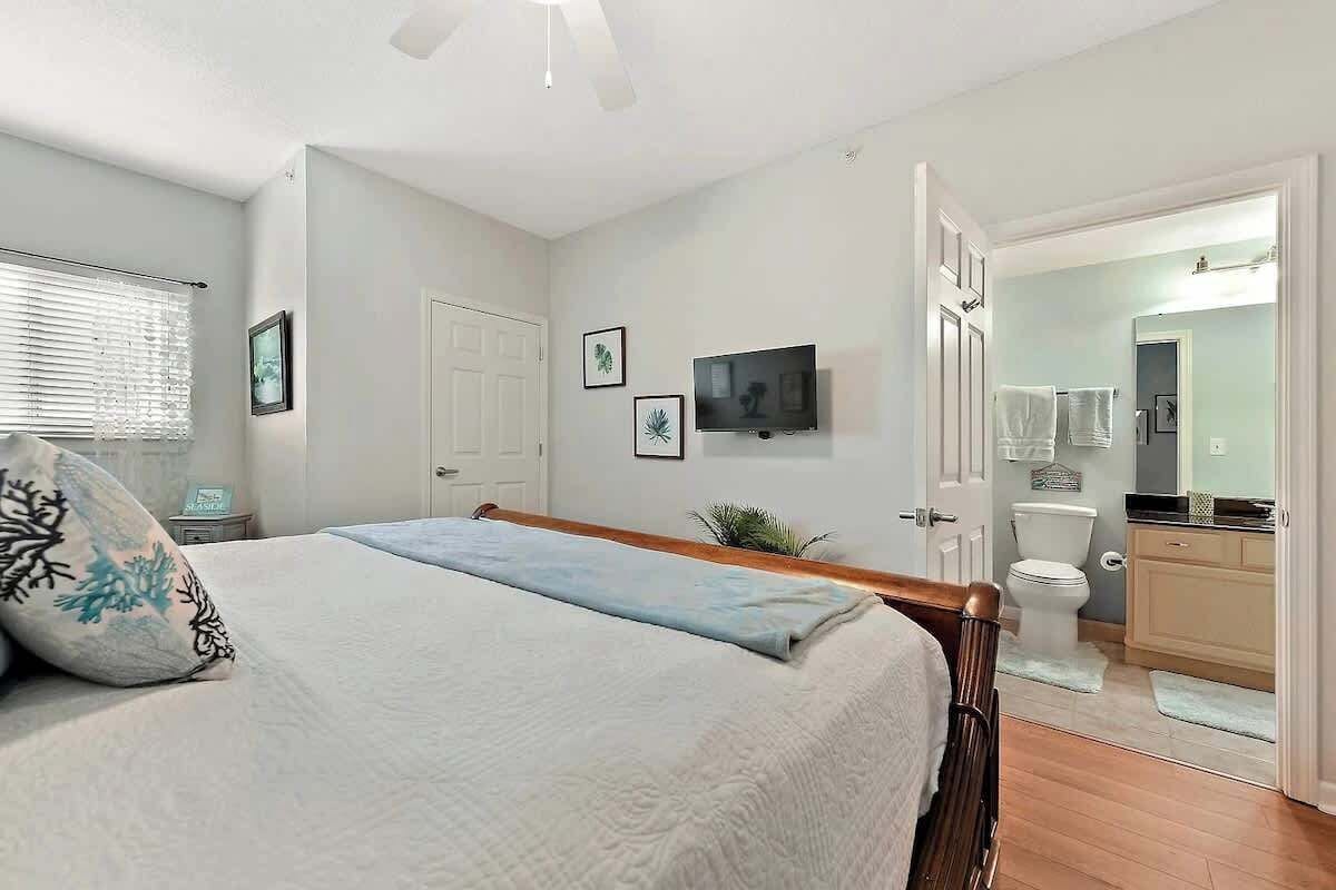 A bedroom with a bed, a television, and a bathroom visible through an open door.