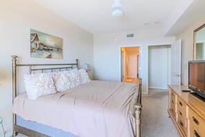 A bedroom with a bed, a television, a dresser, and a painting on the wall. - Beachview Condo in Legacy Tower 1 -1104 - Fully Furnished 2 Bedroom 2 Bath (Gulfport)