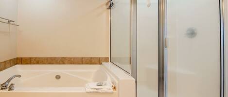 Un baño con bañera, mampara de vidrio y toallero.