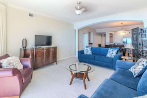 A living room with a sofa, a glass coffee table, a TV, and a cabinet.