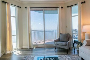 A room with a balcony, a chair, a sofa, and a lamp.