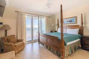 A bedroom with a four-poster bed, a sofa, a TV, and a balcony with curtains. - Spacious Beachview End Unit in Legacy Tower 1 -1101 - 3 Bedroom 3 Bath Condo (Gulfport)