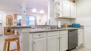 A kitchen with white cabinets, a granite countertop, a blue toaster, and a dishwasher. - Cypress Cove 103 - Beautiful 1 Bedroom 1 Bath Beachfront Condo in Biloxi (Biloxi)