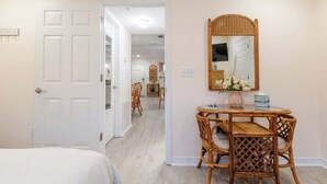A room with a bed, a dining table with chairs, a mirror, and a door leading to another room. - Cypress Cove 103 - Beautiful 1 Bedroom 1 Bath Beachfront Condo in Biloxi (Biloxi)