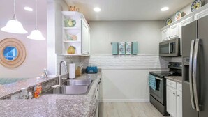 A compact kitchen with granite countertops, stainless steel appliances, and a microwave above the stove. - Cypress Cove 103 - Beautiful 1 Bedroom 1 Bath Beachfront Condo in Biloxi (Biloxi)