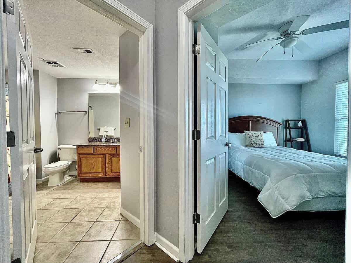A bedroom with a bed, a nightstand, a ceiling fan, and a window.