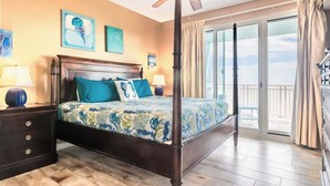 Ein Schlafzimmer mit Himmelbett, Deckenventilator und Balkon mit Vorhängen.