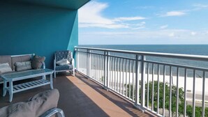 Ein Balkon mit Meerblick, eine Couch, ein kleiner Tisch und ein Stuhl.