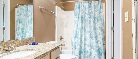 A bathroom with a sink, toilet, and shower curtain.