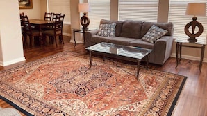 A living room with a sofa, coffee table, and patterned rug. - Legacy Villa 1306 - 2 Bedroom 2 Bath With Garage in Beachside Neighborhood (Gulfport)