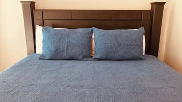 Una cama con cabecera oscura y dos almohadas.