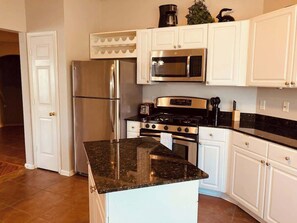 A kitchen with white cabinets, stainless steel appliances, and a granite countertop. - Legacy Villa 1306 - 2 Bedroom 2 Bath With Garage in Beachside Neighborhood (Gulfport)