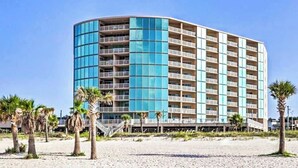 Ett hotell med flera våningar, en böjd fasad, balkonger och ett läge vid stranden.