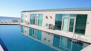 Ett modernt hotell med pool, stora fönster och en fantastisk utsikt över havet.