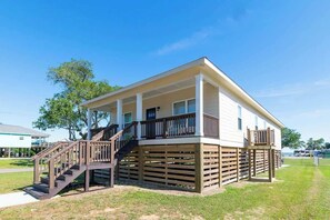 A two-story house with a covered porch, a staircase, and a fenced yard.