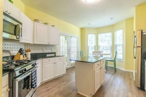 A kitchen with white cabinets, a stove, and a refrigerator.