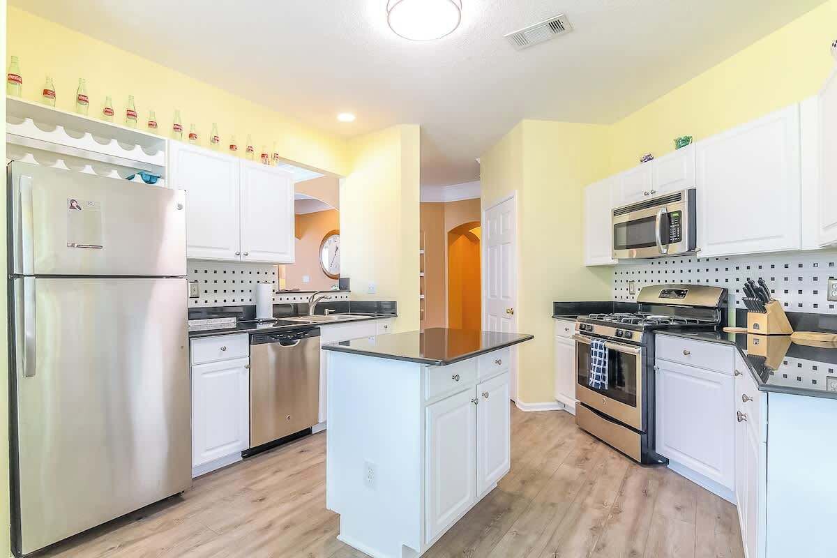 Una cocina moderna con armarios blancos, electrodomésticos de acero inoxidable y una isla central.