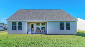 A single-story house with a front porch, a small garden, and a clear blue sky. - Brand New, Fully Furnished 3 Bedroom, 3 Bathroom Home in Ocean Springs! (Ocean Springs)