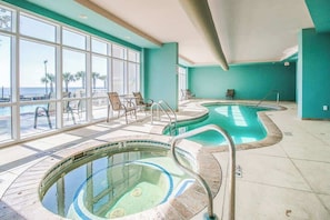 A pool area with two hot tubs, a seating area with chairs, and large windows offering a view of the beach. - Quiet Beachview End Unit in Legacy Tower 2 -309 - 3 Bedroom 3 Bath Condo (Gulfport)